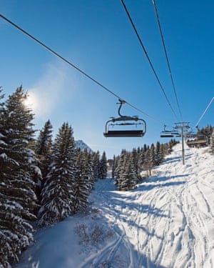 Traveling up an alpine mountainside on ski chair liftPanoramic view of a snow covered alpine mountain range while traveling up on chairlift ski lift in sunlight