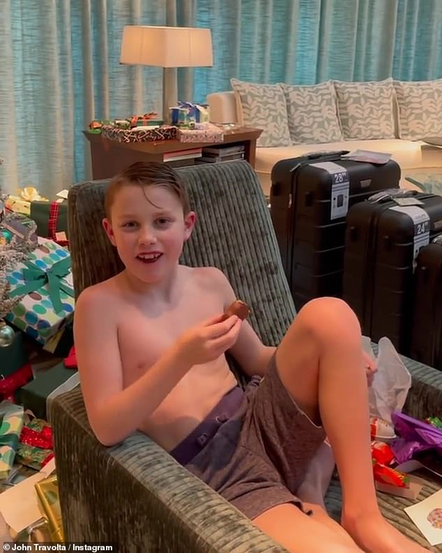 A good snack: His son was eating a cookie as he relaxed in a green corduroy chair