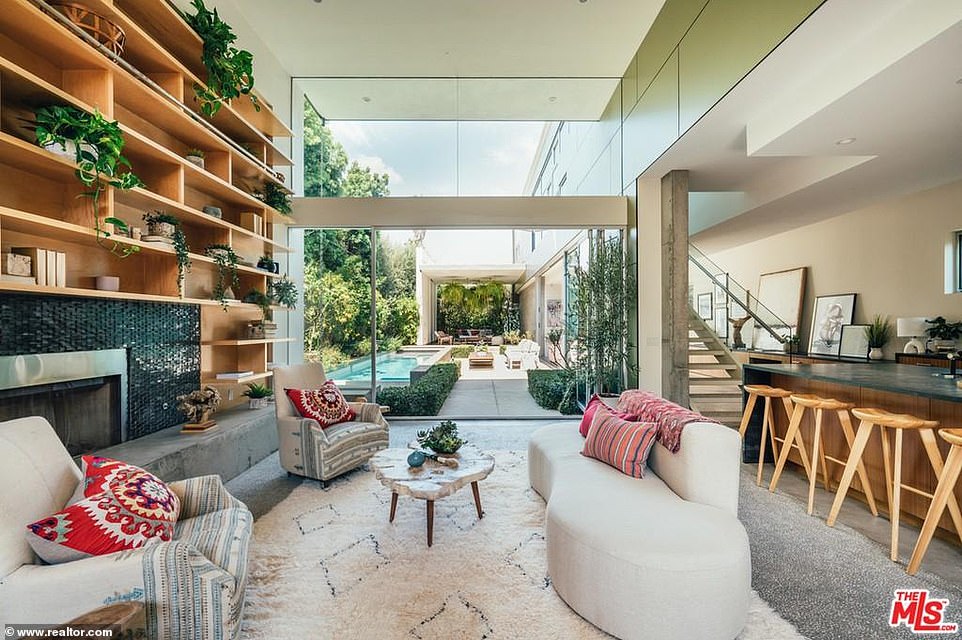 The living room boasts 15-foot high ceilings and sliding glass doors that open onto the back yard. There's a large fireplace surrounded by floor-to-ceiling wood bookshelves