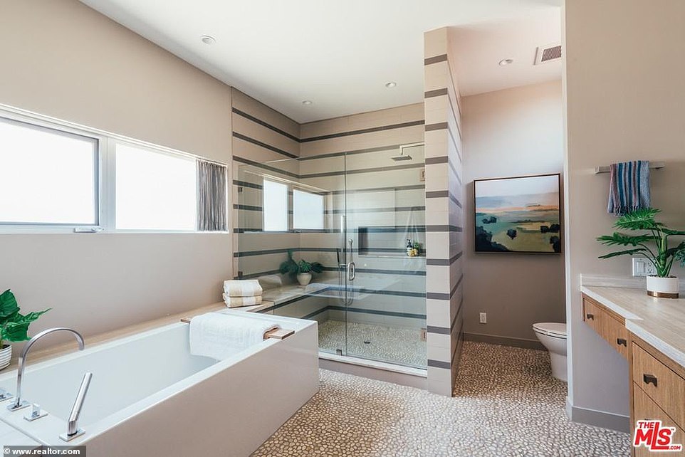 The en suite bathroom offers a rectangular bathtub and a steam shower