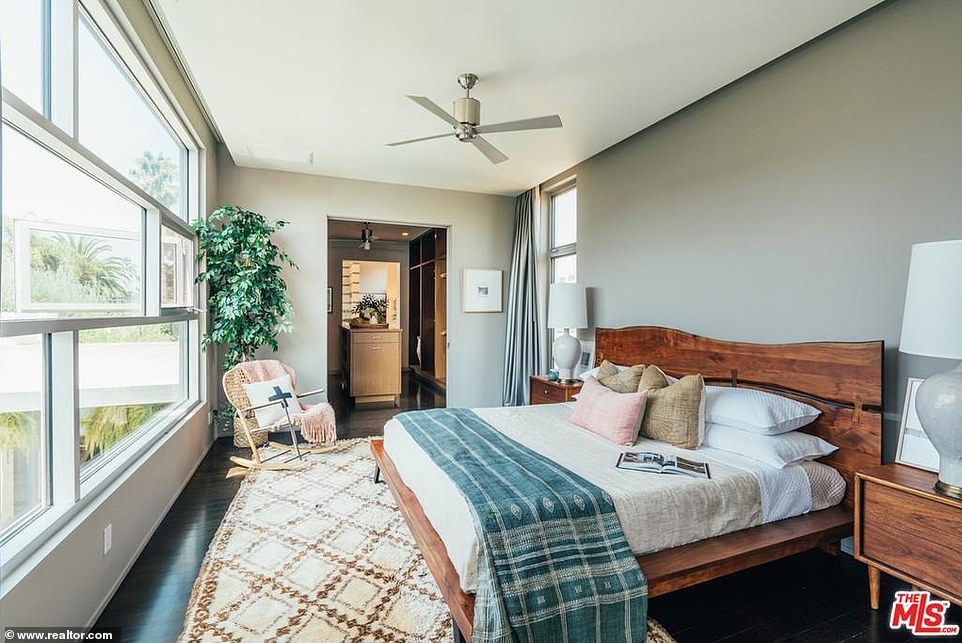 Upstairs, the main bedroom has large windows and dark hardwood floors with a ceiling fan