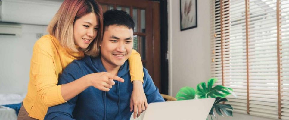 Young couple happy looking at laptop