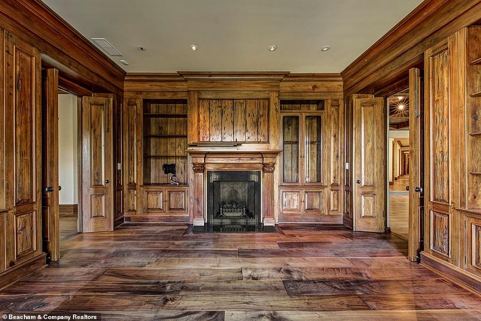 Lovely: The library similarly evokes an old-fashioned feel, with the walls and shelving done entirely in exposed wood and a fireplace set in between the two doors