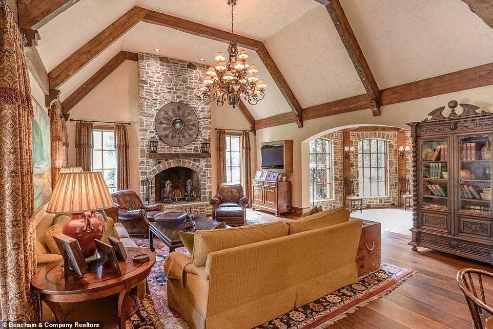 A perfect place for teatime: Another sitting room is arranged around a large stone fireplace and boasts not only an extravagant chandelier but also a massive bookcase as a homey touch