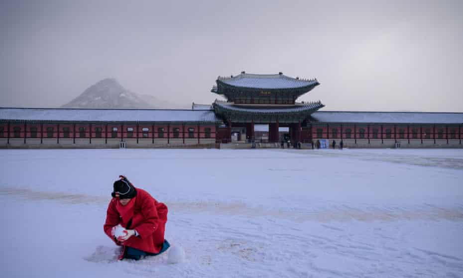 A tour guide makes snowballs in a courtyard of Gyeongbokgung palace, Seoul, South Korea in 2020.