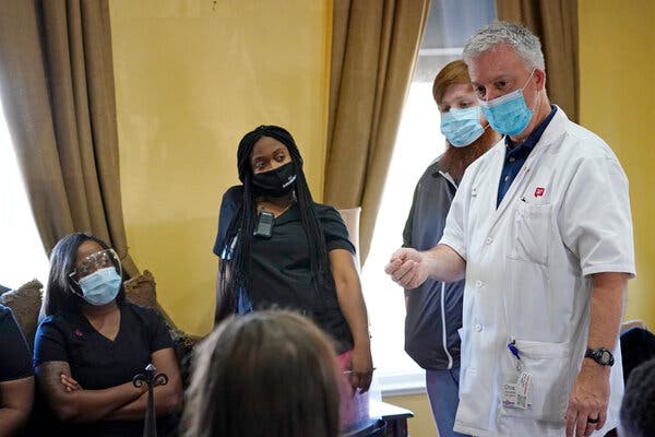 A pharmacist from Walgreens talks to staff members at an assisted living home in Jackson, Miss., about the coronavirus vaccine.