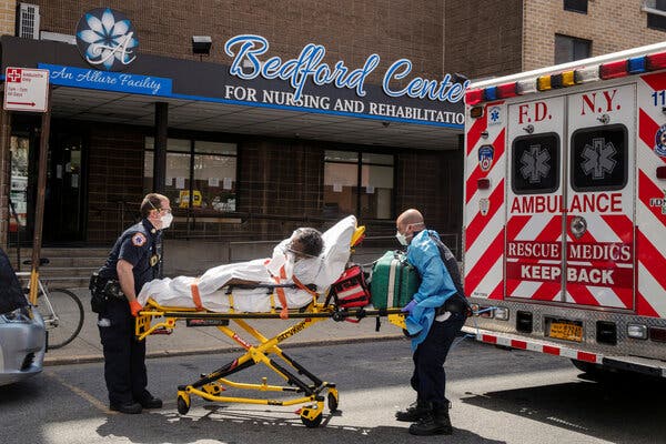 Emergency medical technicians lifting a man after moving him from a nursing home into an ambulance in Brooklyn.