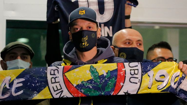 Mesut Ozil hold aloft a Fenerbahce scarf on arrival in Turkey