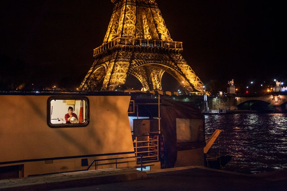 A Filipino domestic worker washes dishes on board a barge along the Seine River in Paris.