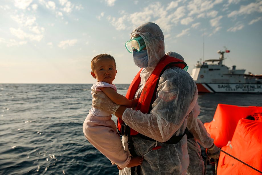 A Turkish coast guard officer carries a child off a life raft during a rescue operation in the Aegean Sea.