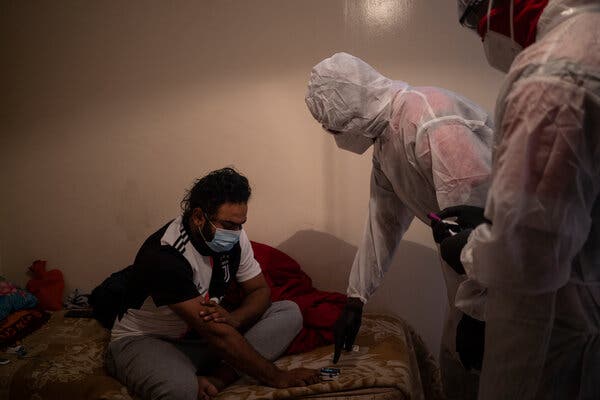 Paramedics caring for a Covid-19 patient at his home in Lenasia, South Africa, last month.