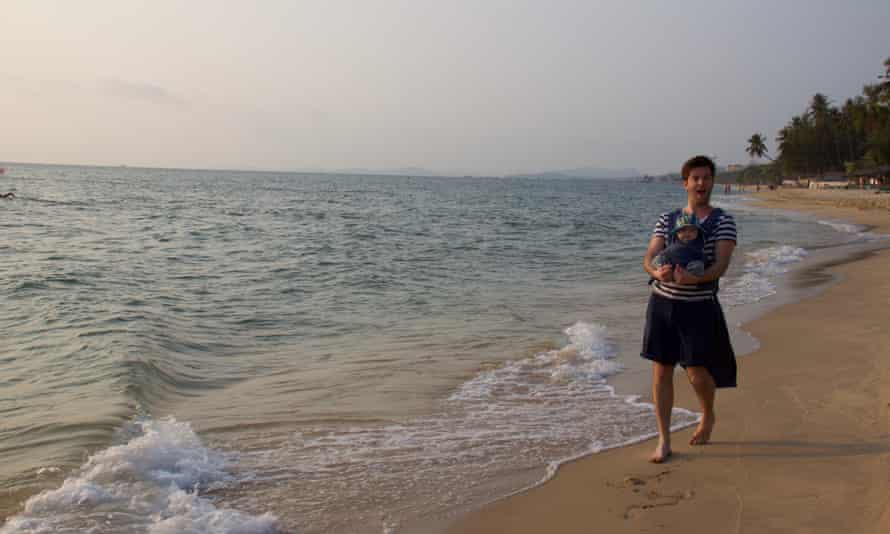 Tom Ravenscroft with his baby on a beach in Vietnam.