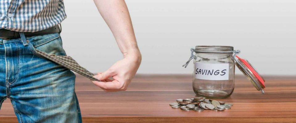 Man showing pocket as no money symbol and jar with coins.