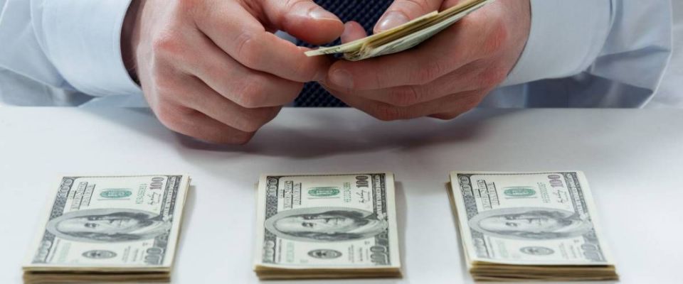 Bank teller&#39;s hands counting dollar banknotes on the table