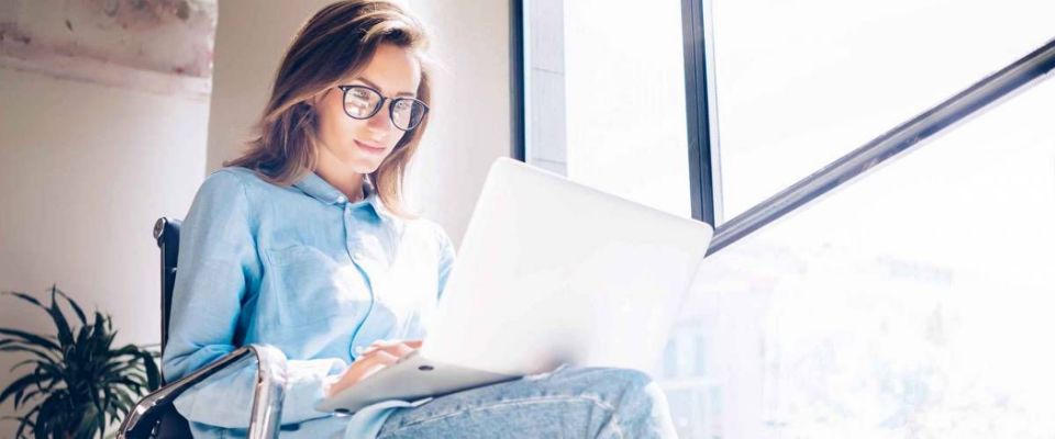 Woman using Laptop in huge Loft Studio to research refinance mortgage rates.