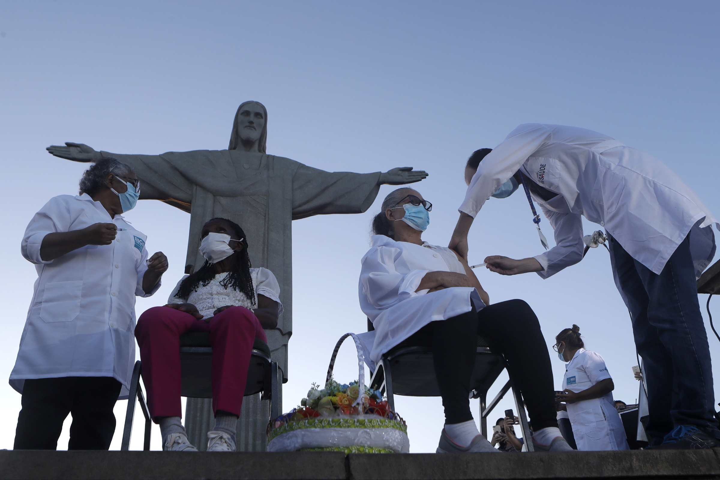 Terezinha da Conceicao, 80, left, and Dulcinea da Silva Lopes, 59, become the first women to receive the COVID-19 vaccine produced by China's Sinovac Biotech Ltd in front of the Christ the Redeemer statue in Rio de Janeiro on Jan. 18, 2021.