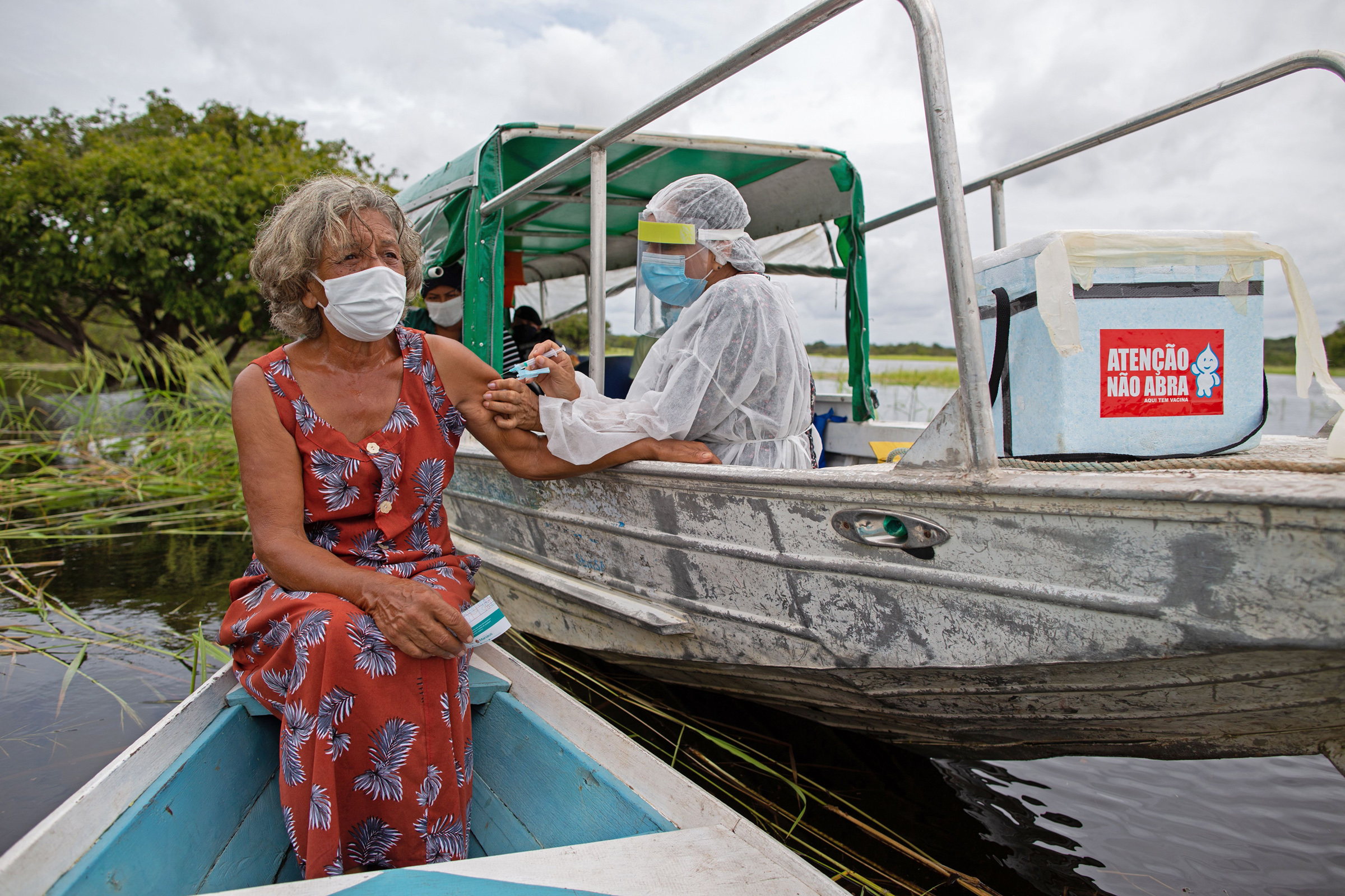 Olga D'arc Pimentel, 72, is vaccinated by a health worker with a dose of the Oxford-AstraZeneca COVID-19 vaccine on the banks of the Rio Negro near Manaus, Brazil, on Feb. 9, 2021.