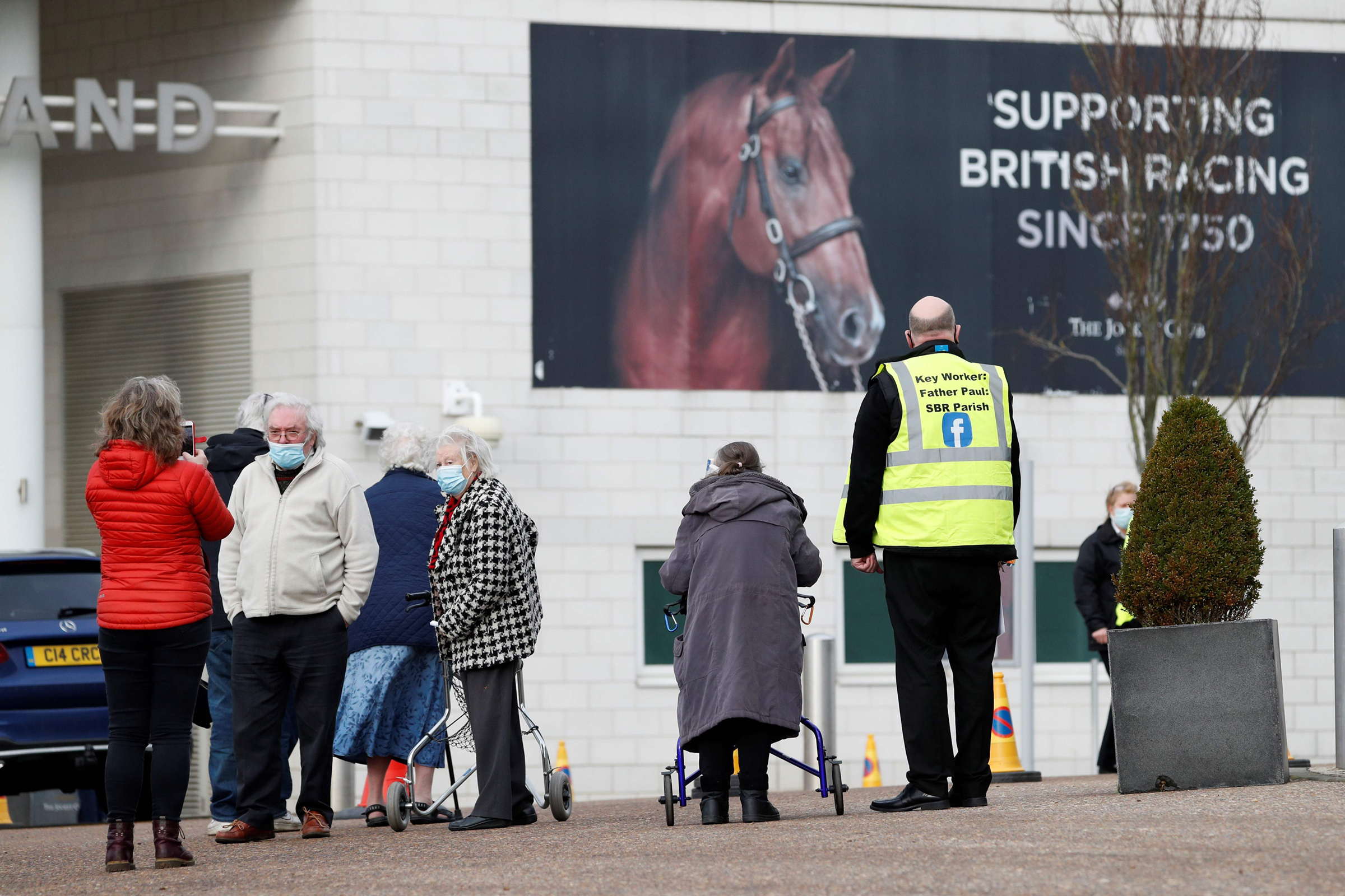 People arrive at Epsom Downs Racecourse as it opens as a COVID-19 vaccination center in Epsom, England, on Jan. 11, 2021.