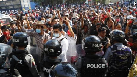 Residents and protesters face riot police as they question them about recent arrests made in Mandalay, Myanmar,  February 13, 2021. 