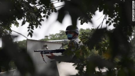 A police officer aims a gun towards protesters during a demonstration against the military coup in Mandalay.