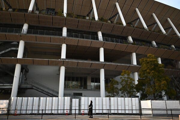 A woman walks outside the National Stadium, the main venue for the opening and closing ceremonies for the Summer Olympics Games in Tokyo on February 11, 2021.