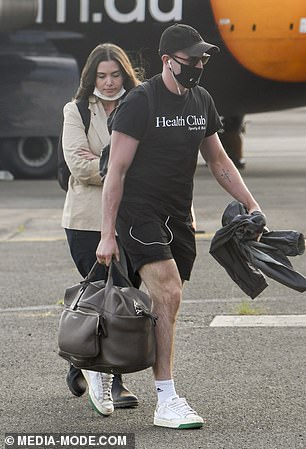 Flight fashion: He teamed an all-black ensemble of sports shorts and a T-shirt with white Adidas ankle-length socks and white trainers