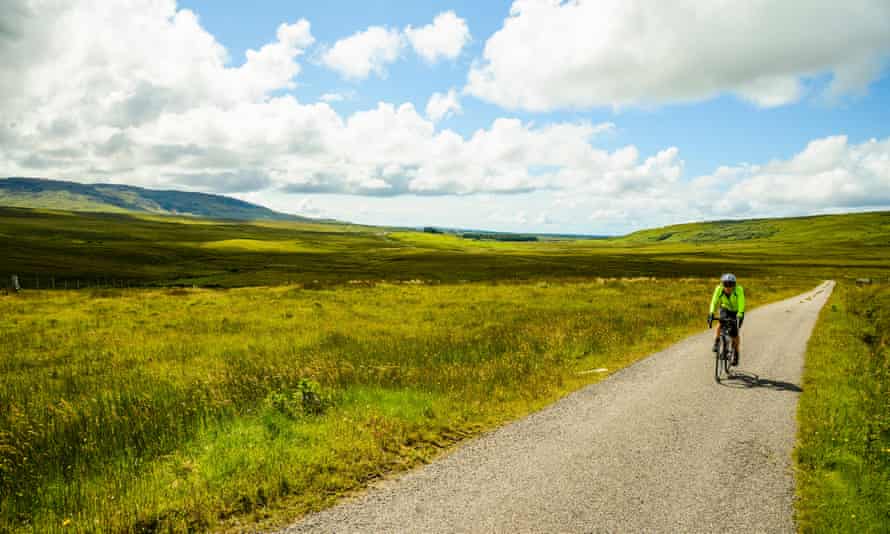 Female cyclist on empty road on the island of Islay Scotland