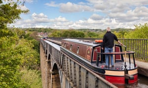 Man with his hand on the tiller, steering narrowboat over the Pontcysyllte Aqueduct