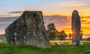 The sun melts away the dawn mist as it rises behind the ancient Sarsen Stones at Avebury in Wiltshire on a calm morning