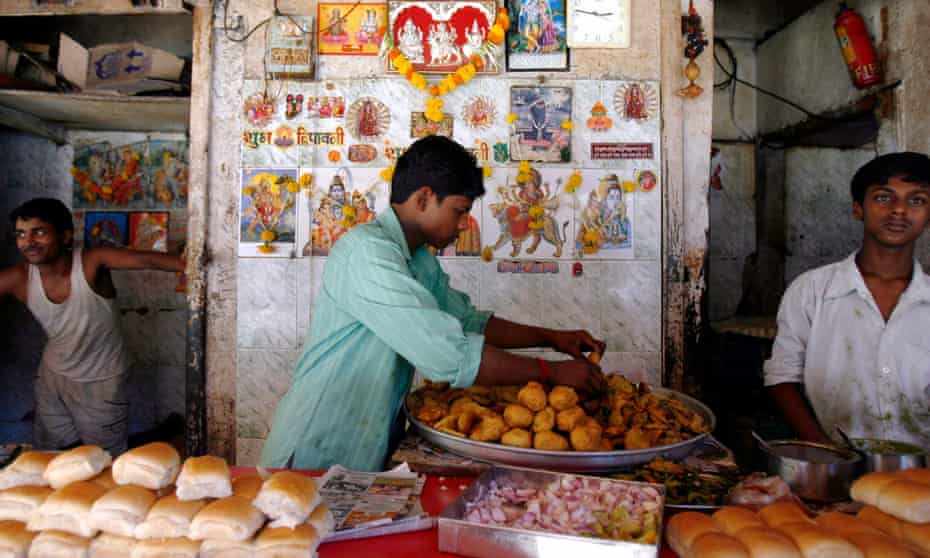 A street stall selling vada pav, a spicy fried potato ball served in a bun.