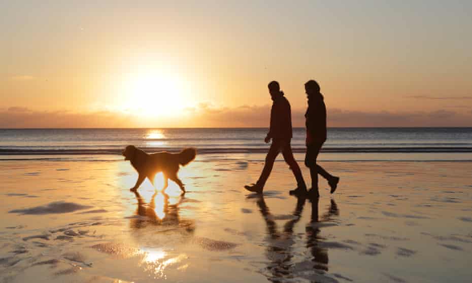 Couple walking do on beach at sunset