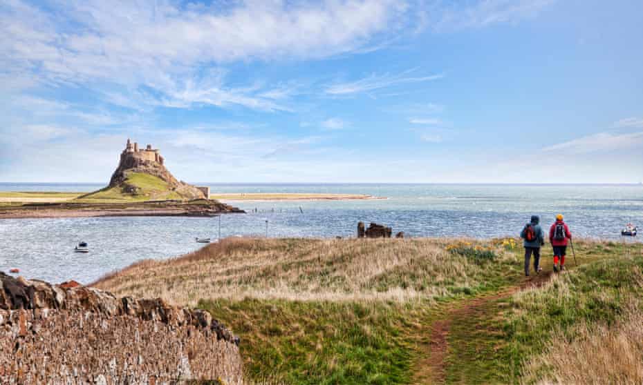 Hikers walking on the Lindisfarne Heugh, Holy Island, Northumberland, England, UKFY4KK7 Hikers walking on the Lindisfarne Heugh, Holy Island, Northumberland, England, UK