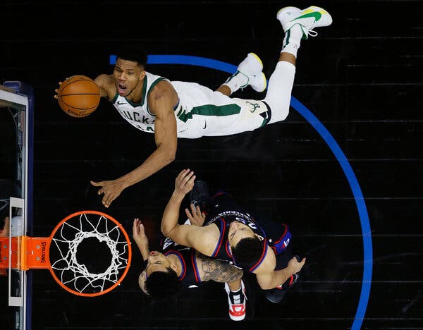 Giannis Antetokounmpo of the Milwaukee Bucks goes up for a shot against Ben Simmons and Danny Green of the Philadelphia 76ers. Sports fans can buy, sell and collect digital “moments” on N.B.A. Top Shot.