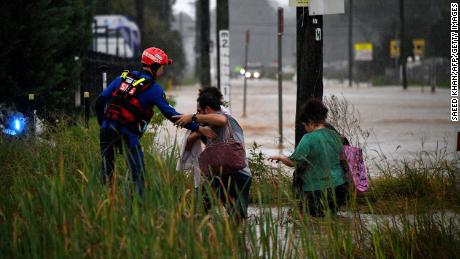 A rescue worker helps residents cross a flooded road in western Sydney on March 20