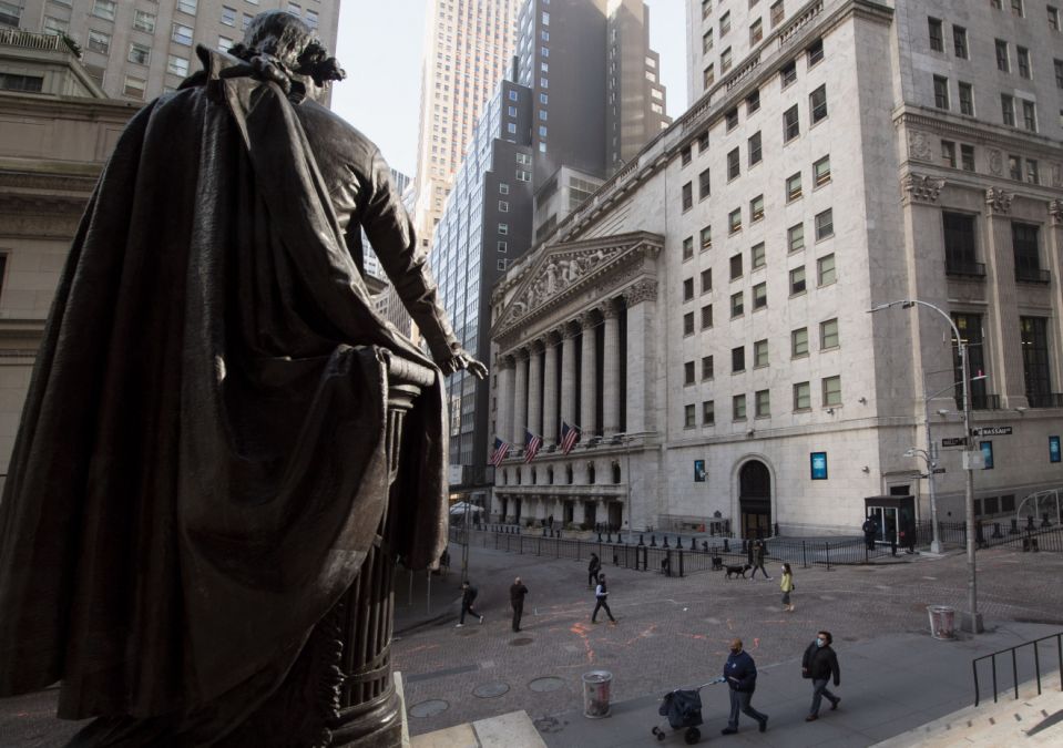 People walk past the New York Stock Exchange (NYSE) and a  statue of George Washington at Wall Street on March 23, 2021 in New York City. - Wall Street stocks were under pressure early ahead of congressional testimony from Federal Reserve Chief Jerome Powell as US Treasury bond yields continued to retreat. (Photo by Angela Weiss / AFP) (Photo by ANGELA WEISS/AFP via Getty Images)