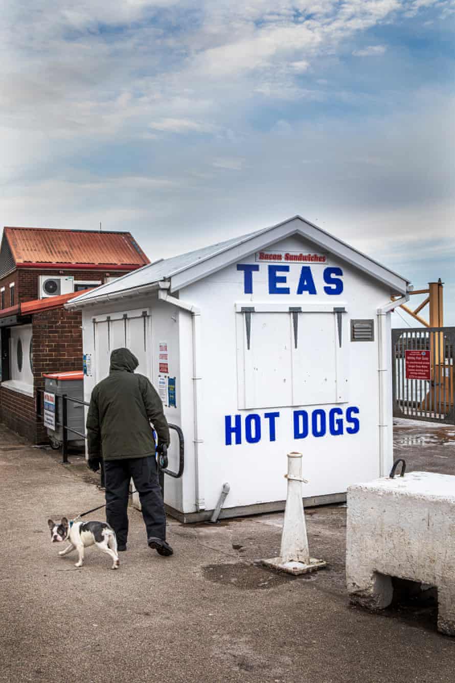 A man walks his dog past the many small food and drink outlets that have remain closed at the harbour in Whtiby.