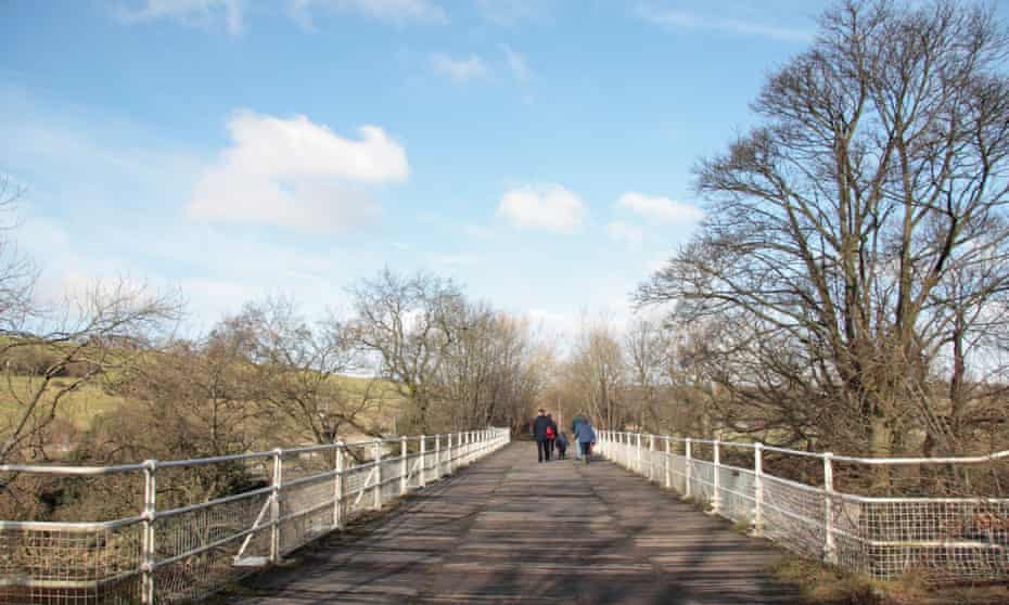 Walkers crossing the old railway bridge over the Swale by Easby Abbey, outside Richmond, North Yorkshire.