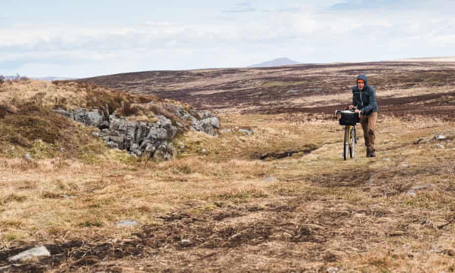 The author pushing his bike over rough ground to the Chartist Cave