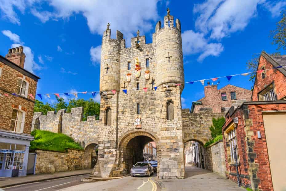 Micklegate, York, UK, on a blue-sky day;  a car drives through the gate.