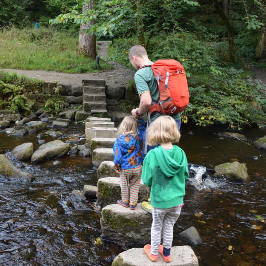 Two children and an adult cross a stream using stepping stones, Hardcastle Crags, West Yorkshire, UK.