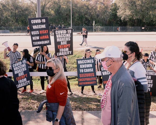 Anti-vaccine protesters shouted and waved signs at health care workers in Tampa, Fla., on Sunday as they entered Raymond James Stadium to watch the Super Bowl.