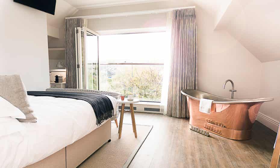 A bed facing a large window and a gold, roll-top bath at Brocco on the Park, Sheffield