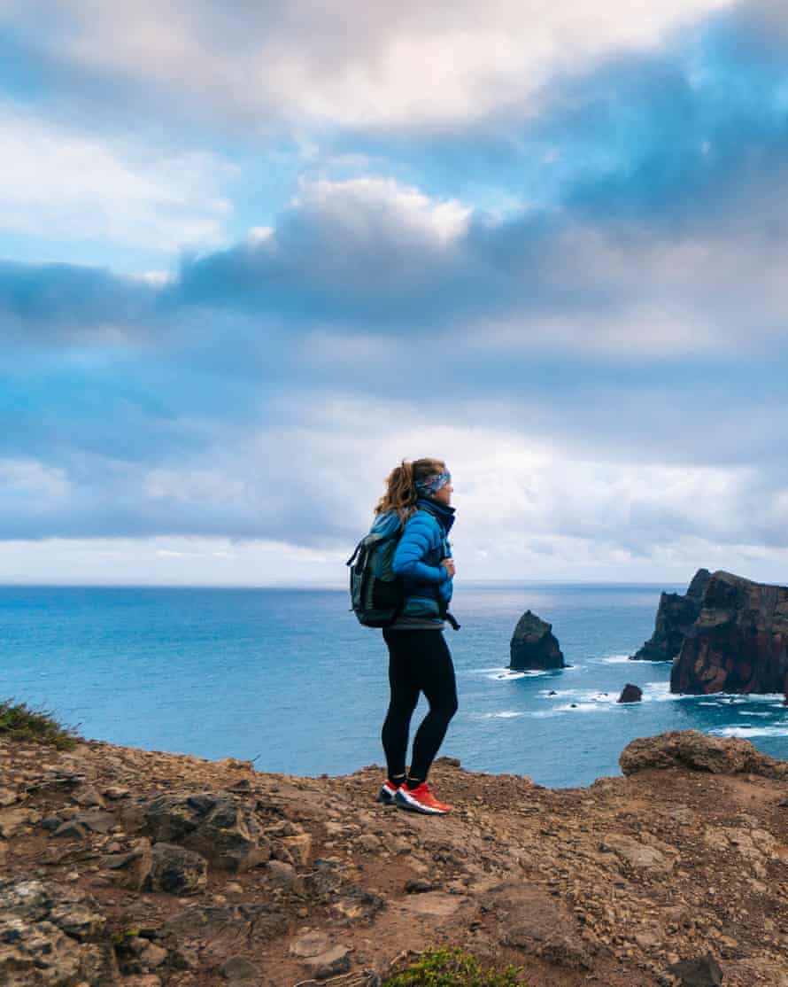 Female trail runner pauses to enjoy view above the coastline of Ponta de São Lourenço.