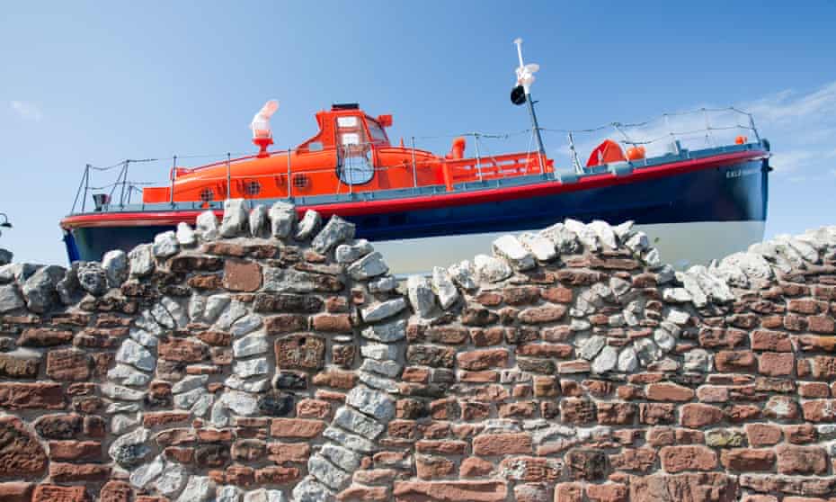 An old lifeboat and a stone wall made to look like waves outside the Dock Museum in Barrow in Furness