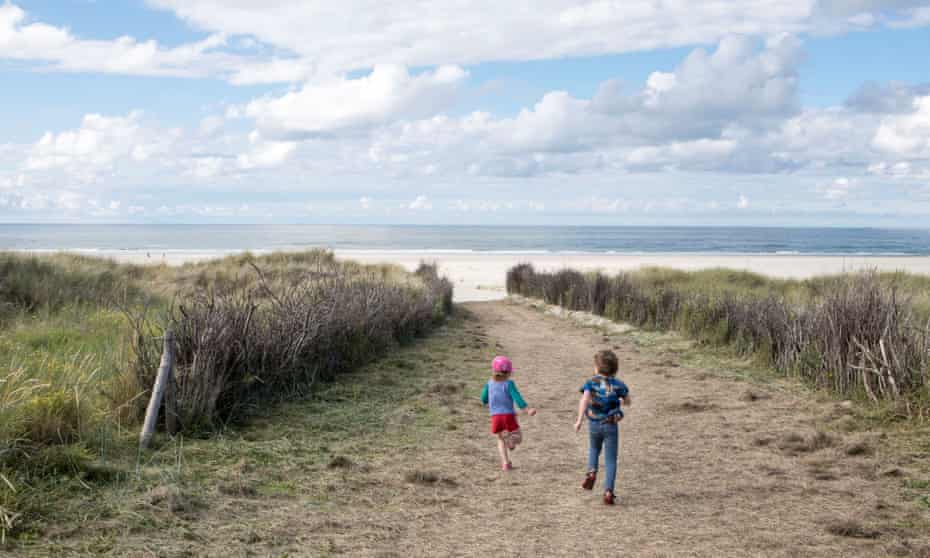 Children run through the dunes to the beach on Juist island, Geramny