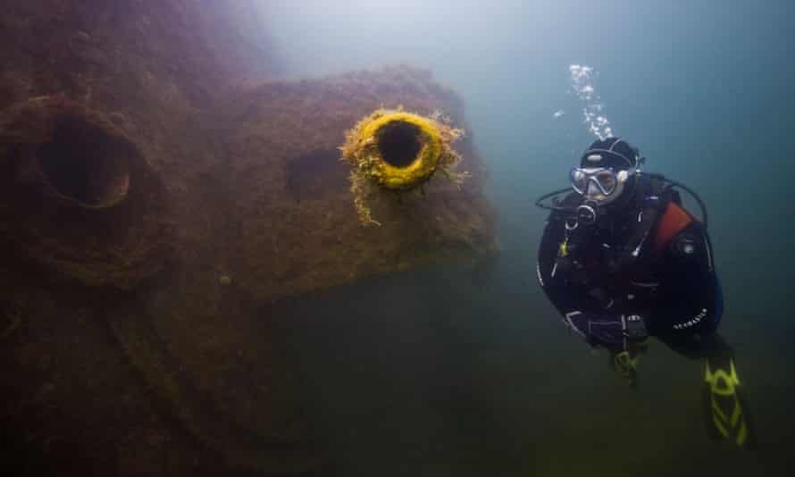 A diver inspects a four-inch gun of a German destroyer in Scapa Flow.