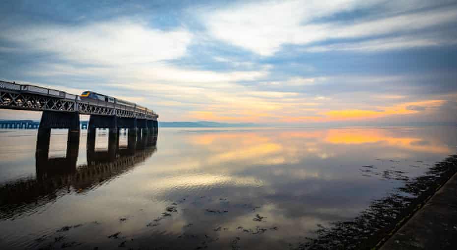 Train crossing a calm Tay estuary at sunset, Dundee, Scotland, United Kingdom.