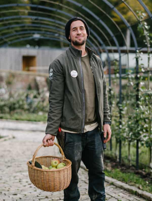 A man carrying a basket of apples and smiling