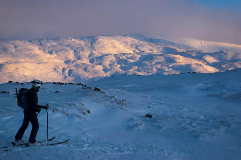 The sun sets on the first day of skiing as a skier look out to Meall Odhar.